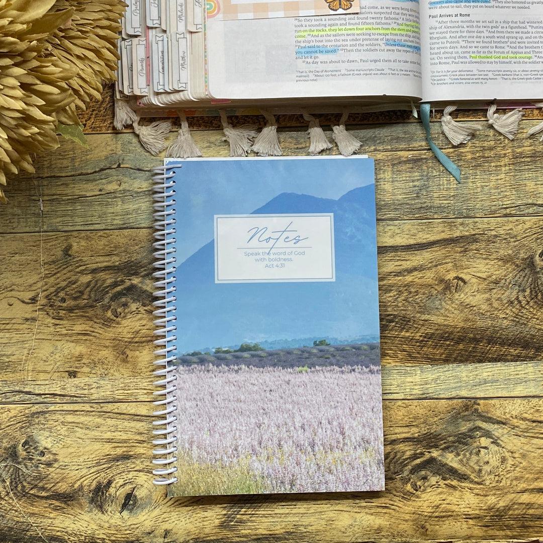 Open book with a notebook and decorative flowers on a wooden surface