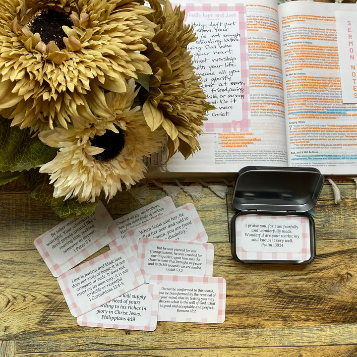 Open book with prayer cards and sunflowers on a wooden surface
