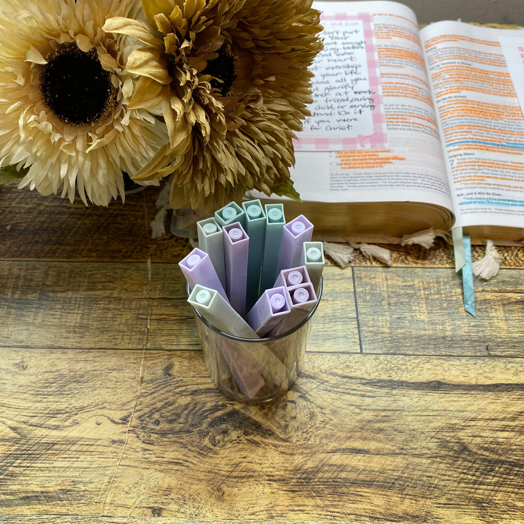 Open book with colorful markers and sunflowers on a wooden surface