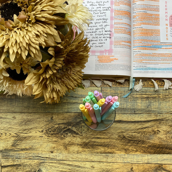 Open book with colorful pens and sunflowers on a wooden surface