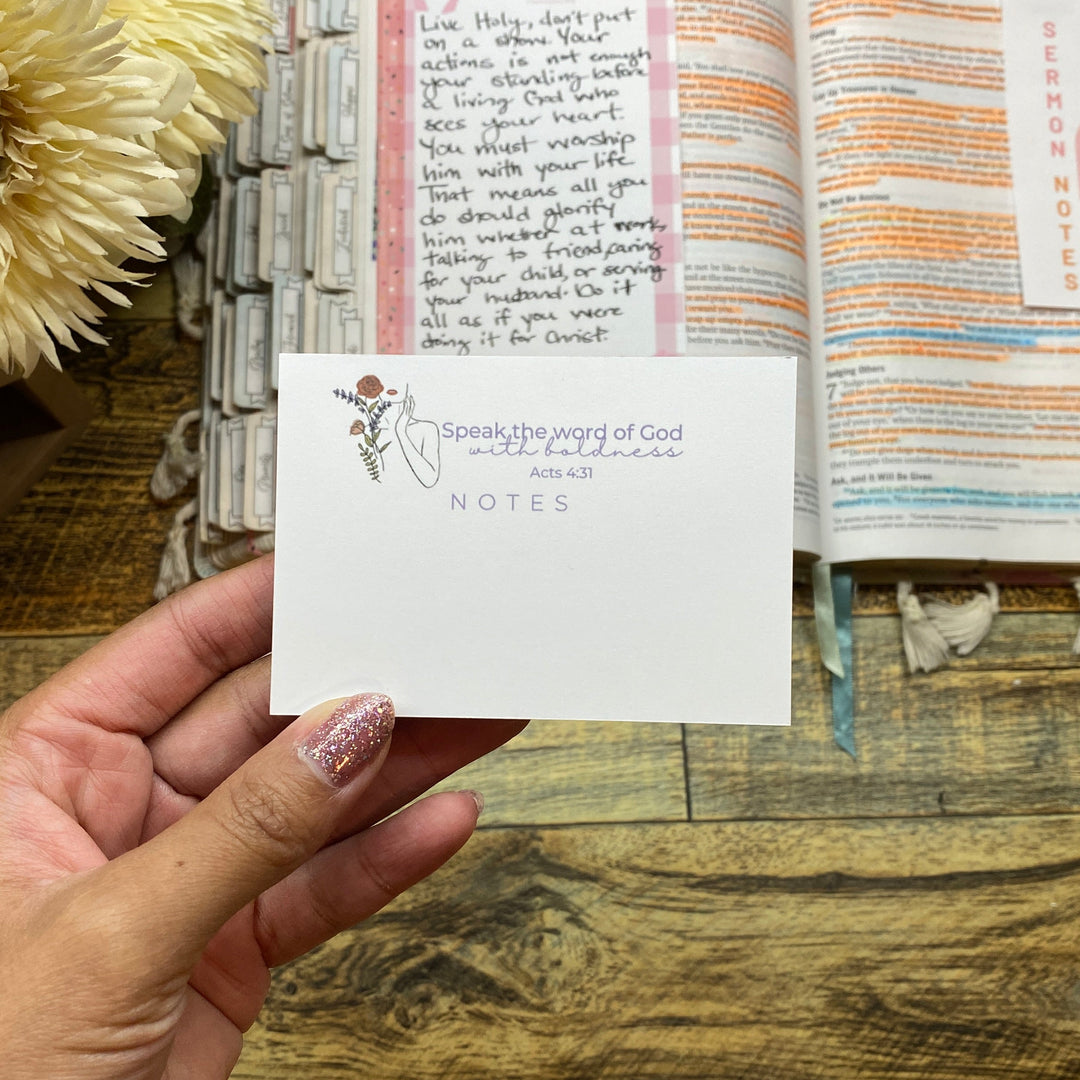 Hand holding a card over an open book with decorative elements on a wooden surface