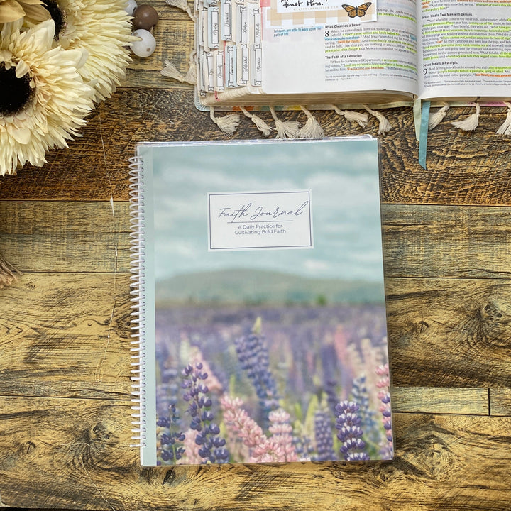Notebook with floral cover on a wooden surface next to an open book.