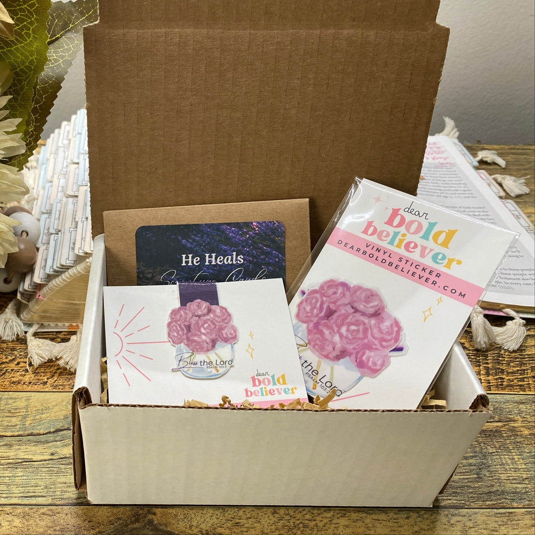 Box containing greeting cards with floral designs on a wooden surface with flowers in the background.