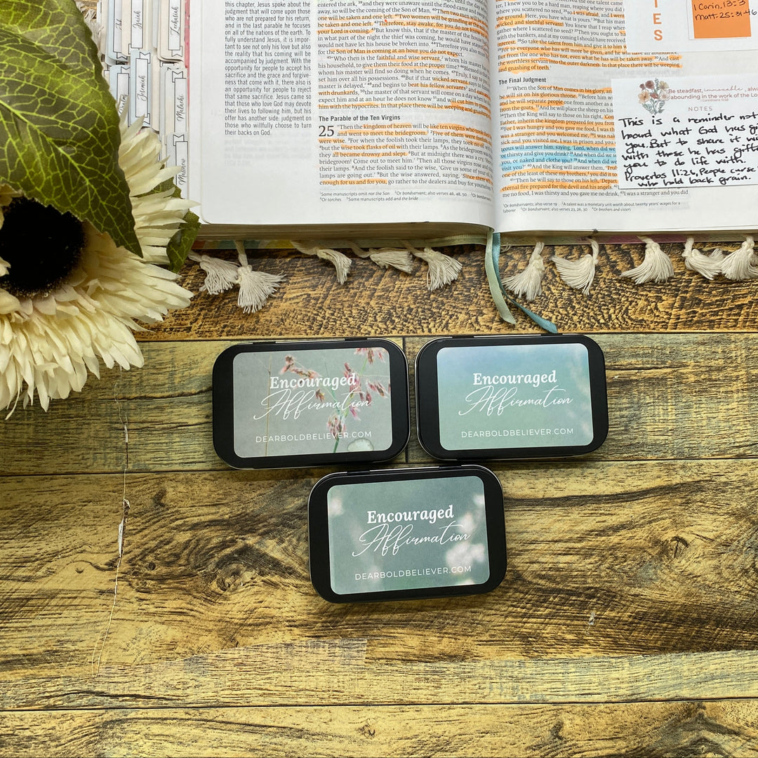 Three small rectangular items with text on a wooden surface next to an open book.