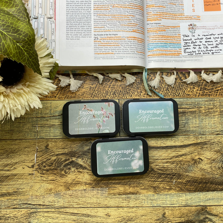 Three small rectangular items with text on a wooden surface next to an open book.