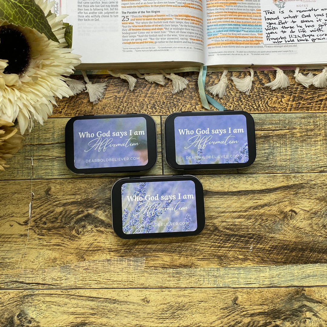 Three small rectangular items with text on a wooden surface next to an open book and sunflowers.