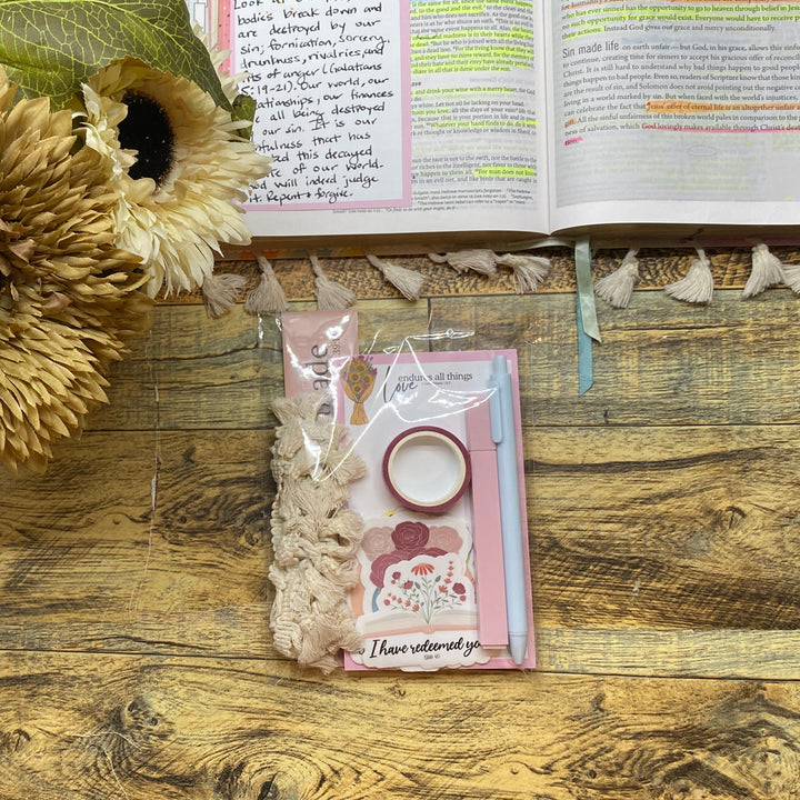 Wooden desk with sunflower arrangement, stationery items, and open book.